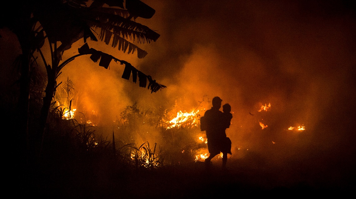Uomo indonesiano corre con le fiamme alle spalle